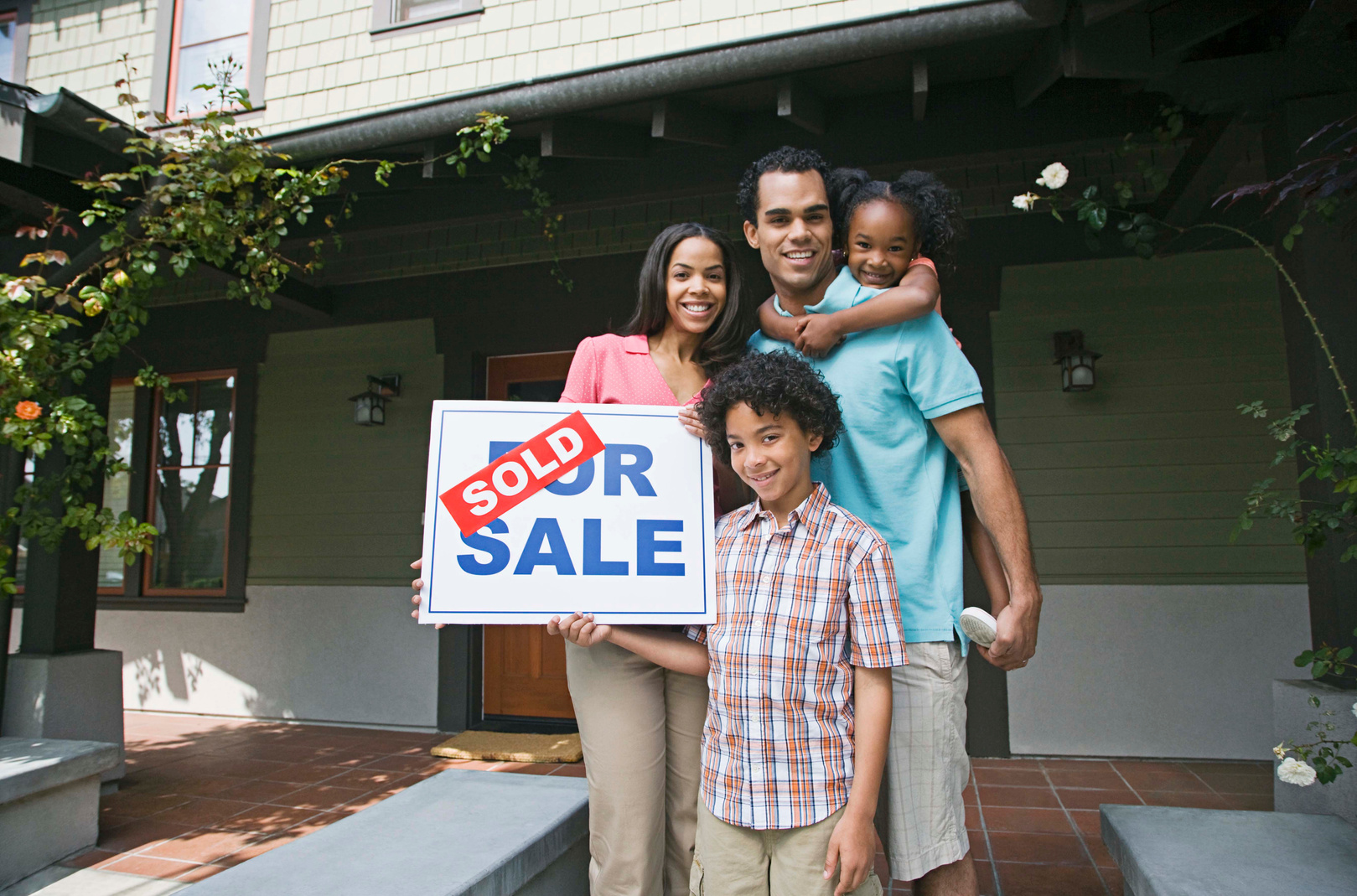 Family with house and sold sign